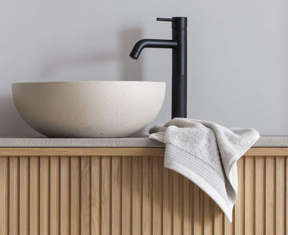 Modernes Beton-Waschbecken auf einer passenden Betonplatte, elegant präsentiert auf einem hochwertigen Eichen-Badmöbel. Ein Zusammenspiel von Robustheit und Natürlichkeit.