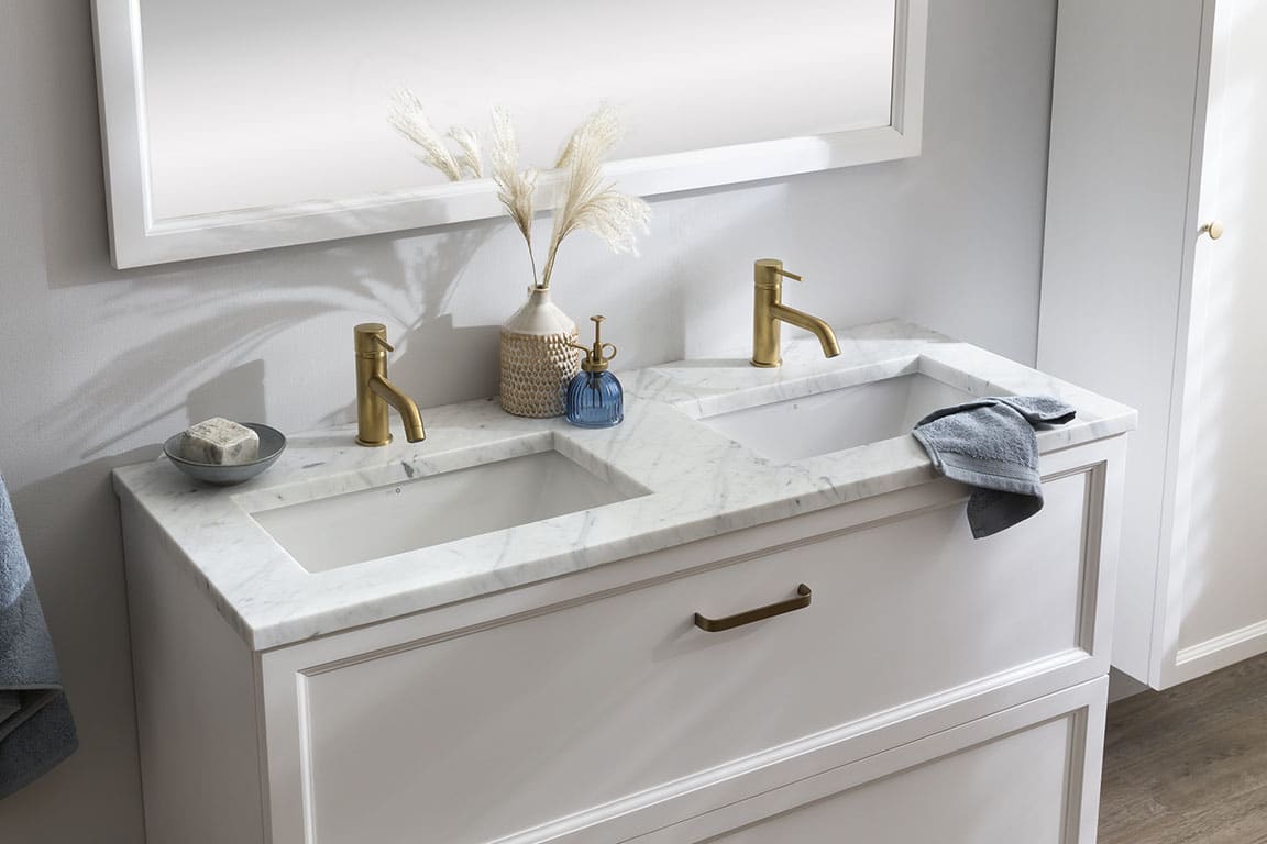Stehender Waschtisch im klassischen Stil mit Marmor-Waschtischplatte und goldenen Armaturen.