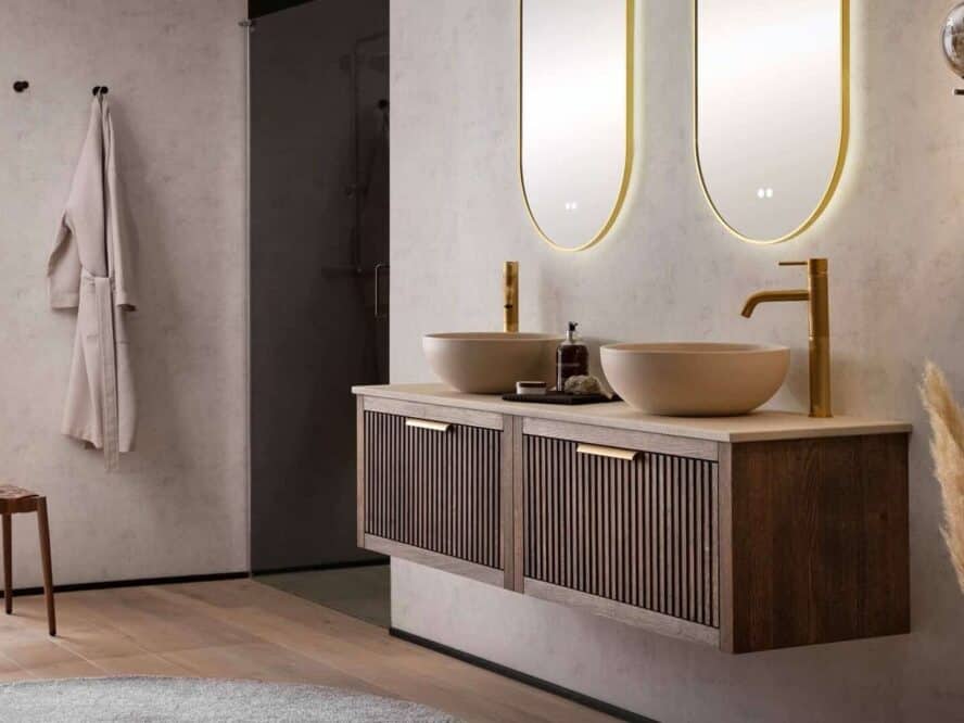 Eiken badkamermeubel in 160 cm in de kleur donker eiken. Het meubel is van massief eiken met daarboven een beton beige blad met twee beige betonnen kommen en twee gouden kranen. Boven het badmeubel hangen twee gouden ovalen spiegels