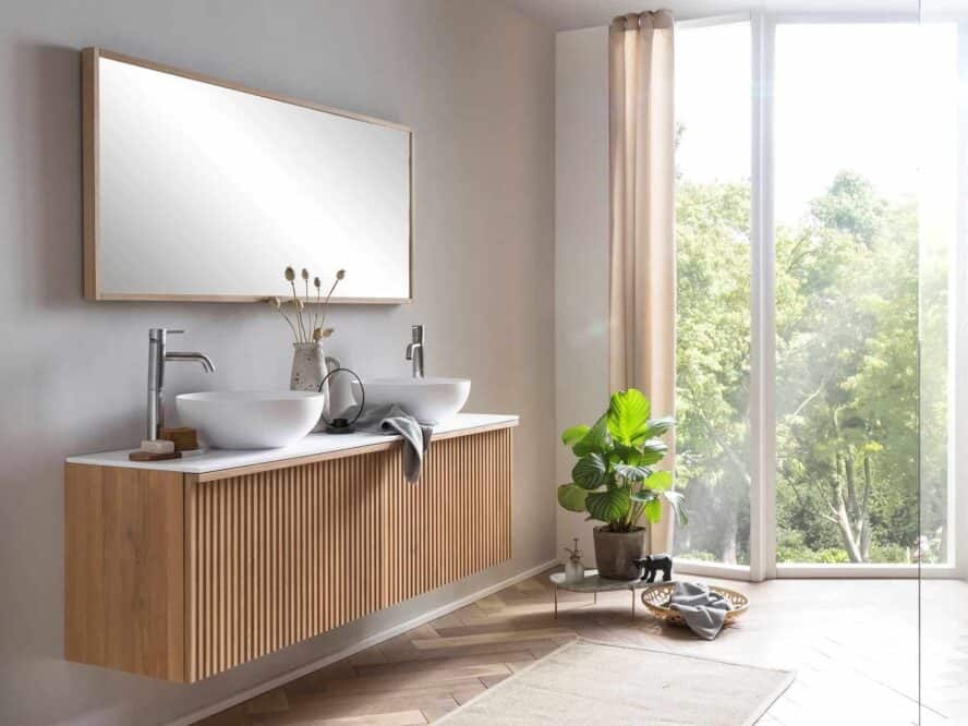Hängendes Badmöbel in 160 cm mit Rillenfront aus Eichenholz. Das Möbel verfügt über eine Waschtischplatte aus Solid Surface und zwei Solid-Surface-Aufsatzwaschbecken.