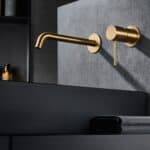 Moderne Waschtischarmatur Wandmontage in Gebürstetes Gold, für die Montage über Waschtisch oder Aufsatzwaschbecken, als Komplettset inklusive passendem Click-Clack-Verschluss mit langlebiger PVD-Beschichtung. Der Click-Clack-Verschluss lässt sich durch Dr