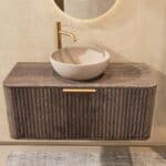 Rundes hängendes Badezimmermöbel 100 cm aus dunkler Eiche mit Riffelfront, Eichenholzplatte und beige Kalksteinbecken