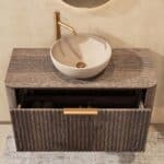 Rundes hängendes Badezimmermöbel 100 cm aus dunkler Eiche mit Riffelfront, Eichenholzplatte und beige Kalksteinbecken