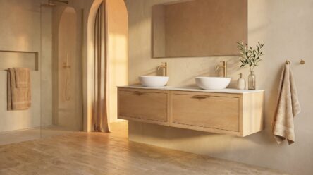 Warmes modernes Landhaus-Badezimmer mit schwebendem Waschtischunterschrank aus Eiche, Doppelwaschtisch mit zwei Aufsatzwaschbecken, goldfarbenen Armaturen und bodengleicher Dusche in beigen Naturtönen.