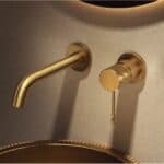 Moderne Waschtischarmatur Wandmontage in Gebürstetes Gold, für die Montage über Waschtisch oder Aufsatzwaschbecken, als Komplettset inklusive passendem Click-Clack-Verschluss mit langlebiger PVD-Beschichtung. Der Click-Clack-Verschluss lässt sich durch Dr