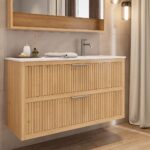 Das Rosenfeld Badmöbel 120 in Eiche natur vereint handwerkliche Präzision mit modernem Luxus. Gefertigt aus massivem Eichenholz mit Rillenfront, zwei Softclose-Schubladen und einem matten weißen Mineralwerkstoff-. Das Waschbecken ist wahlweise mit oder oh
